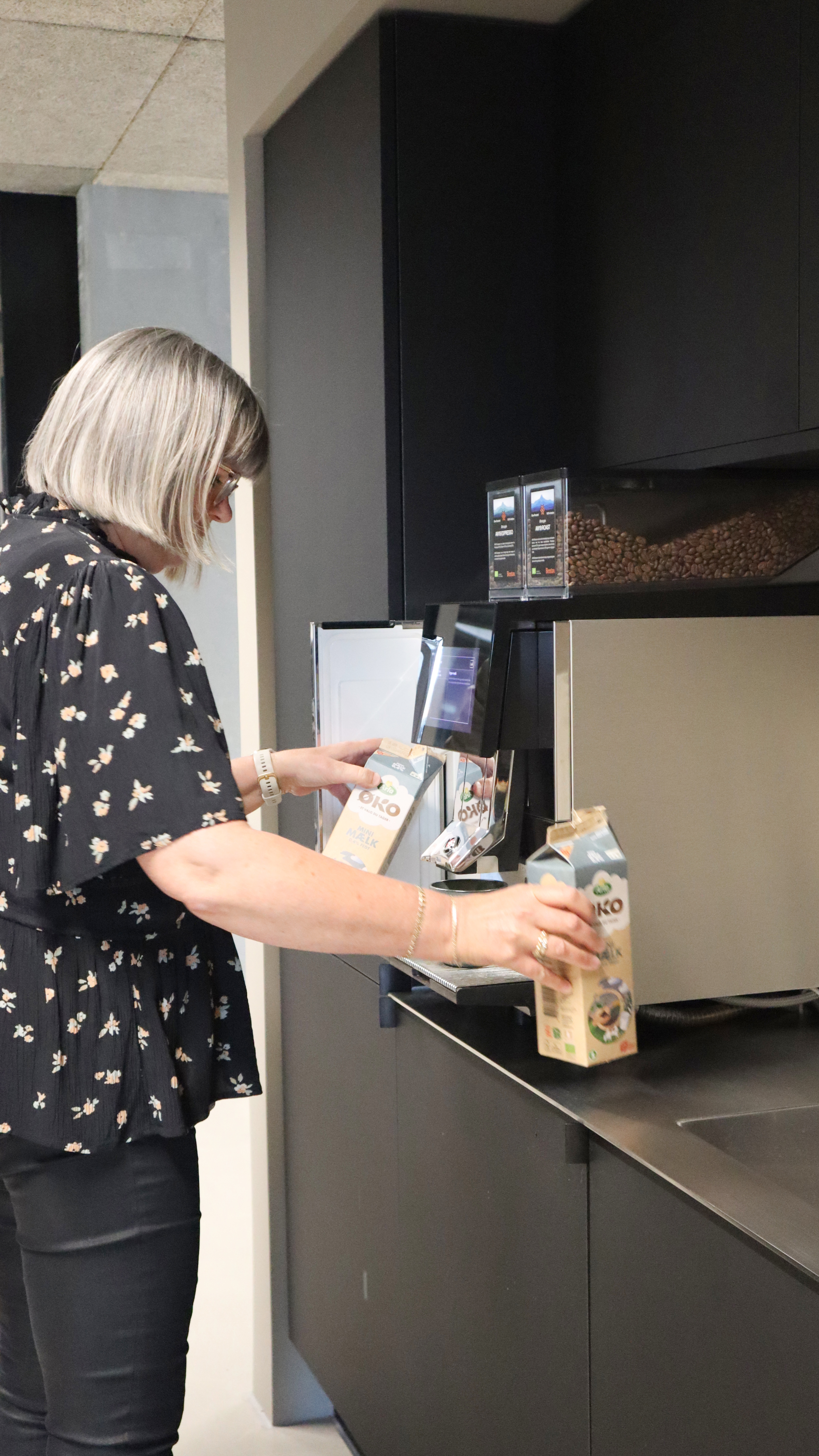 Obtons Front Desk Receptionist, der skifter mælk karton i kaffemaskinen