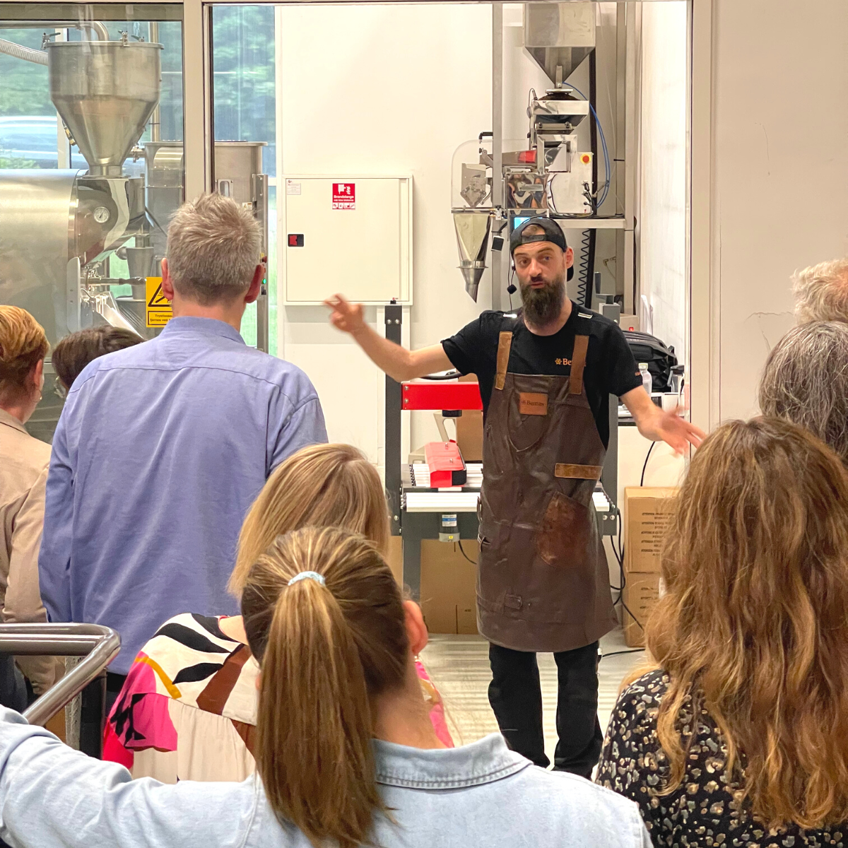 En medarbejder viser folk rundt i Bentax risteriet og fortæller om en god kaffe