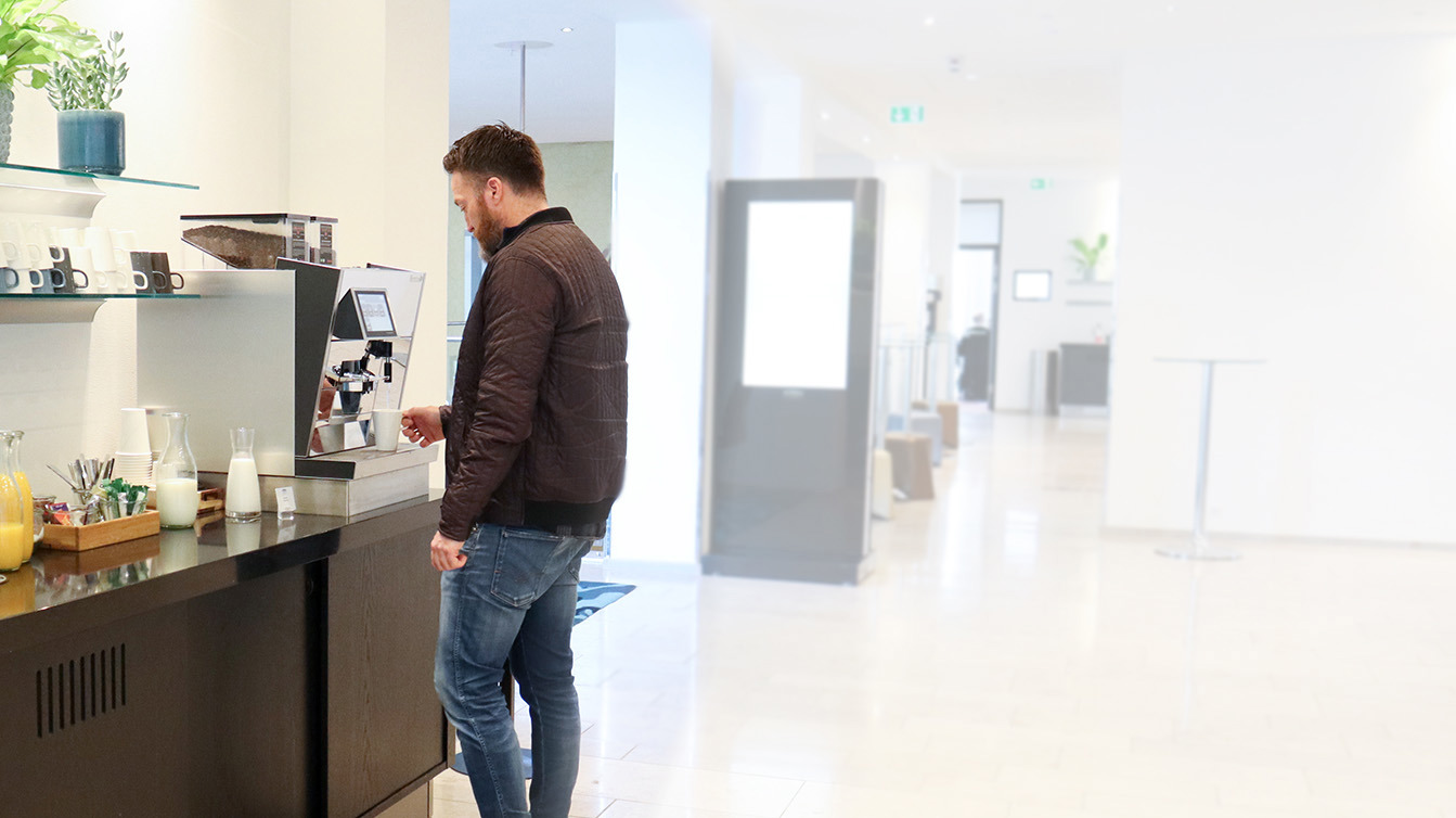 En mand henter en kop kaffe fra en kaffemaskine